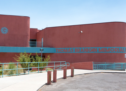 Thomas Branigan Memorial Library in Las Cruces, New Mexico. Red brick structure with curved walls and turquoise signage.