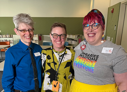 Otter Bowman, Emily Drabinski, and Megan Durham pose together with big smiles in the Daniel Boone Public Library