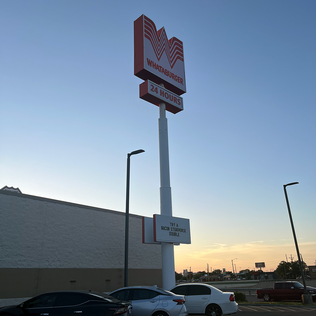 A tall Whataburger sign at dusk.