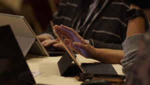 a school librarian uses a tablet while sitting at a table