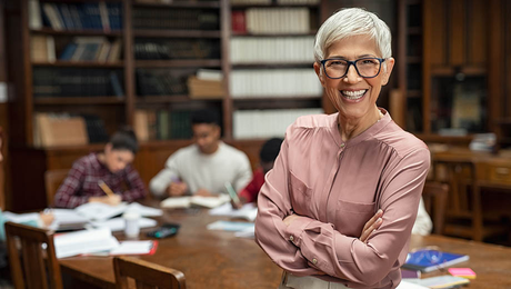 A high school school librarian works at a table with students