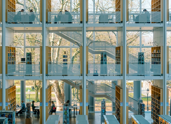 Large library floor-to-ceiling windows with shelves and stairs in the foreground