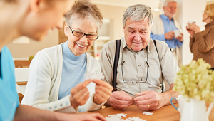 Female and male seniors fitting together blank puzzle pieces with guidance from a female medical professional.