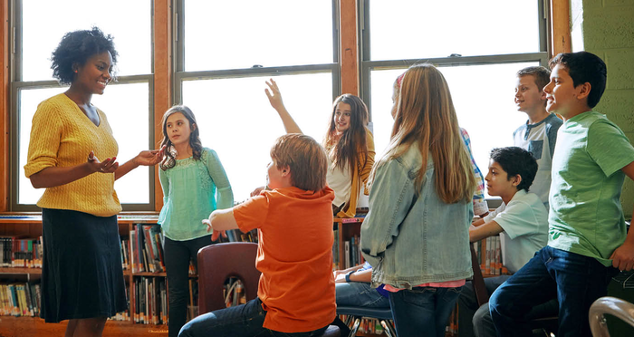 A librarian works with middle school kids in a library