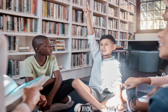 Boy with raised hand in library