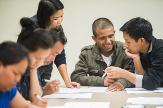 Group of people sitting at a table looking at papers and talking