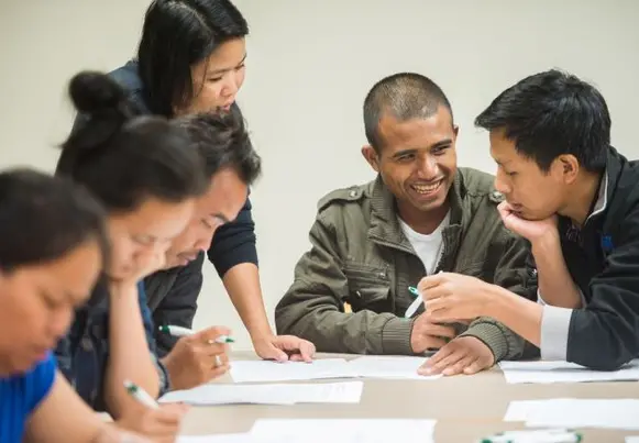 Group of people sitting at a table looking at papers and talking