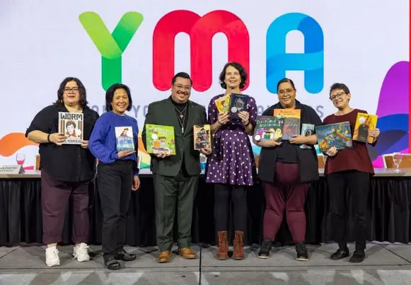 Group of people holding books in front of backdrop that says YMA